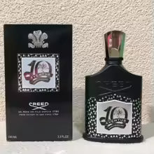 Two black Creed perfume bottles with decorative labels on a textured beige background