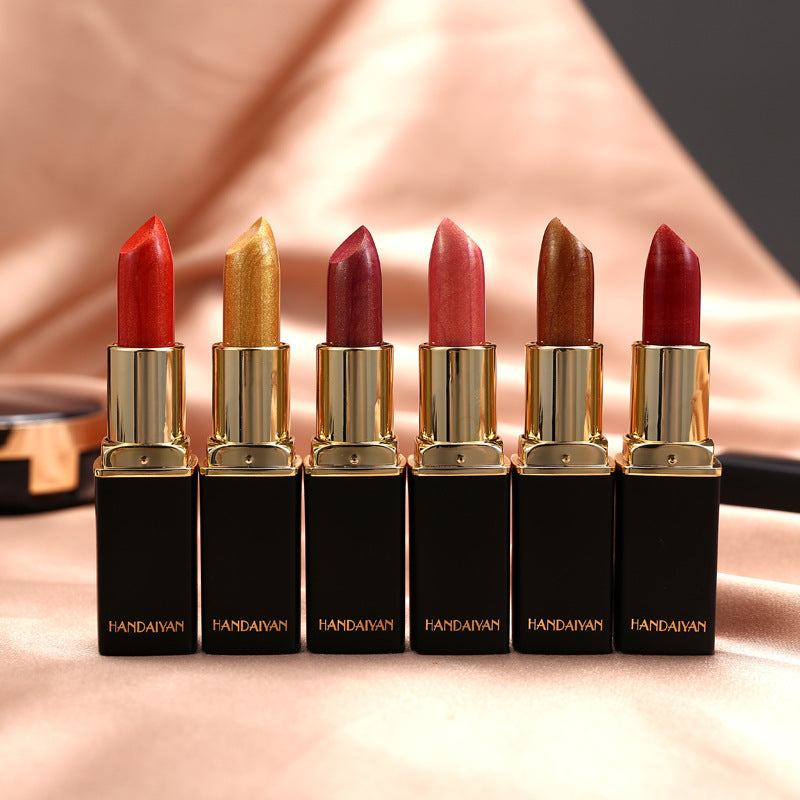 Set of six lipsticks with gold caps and black cases on a reflective surface.
