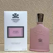 Pink Creed perfume bottle and packaging on a beige background