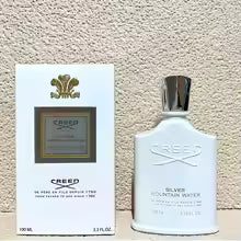 Creed Silver Mountain Water perfume bottle with packaging on a textured beige background