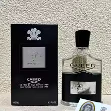 Creed perfume bottle and packaging on a textured surface
