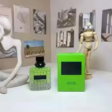 Green bottle and box with black cap on a white surface with decorative items in the background