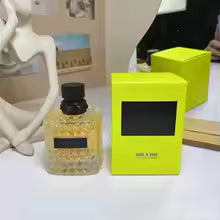 Yellow packaging box with a black label next to a small bottle on a white surface.