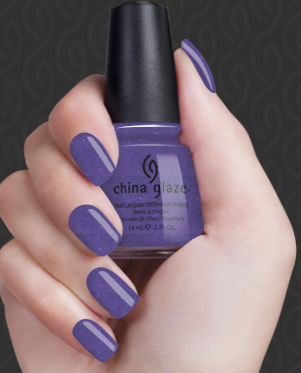 Hand with purple nail polish holding a China Glaze nail polish bottle against a dark background