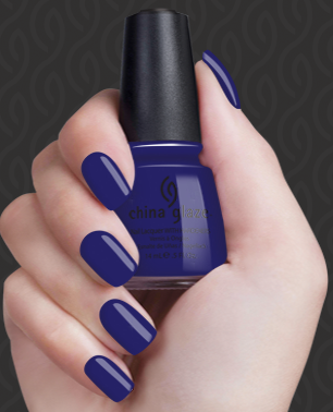 Hand with blue nail polish holding a bottle of blue nail polish.