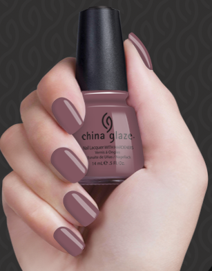 Hand with purple nail polish holding a China Glaze nail polish bottle against a dark background