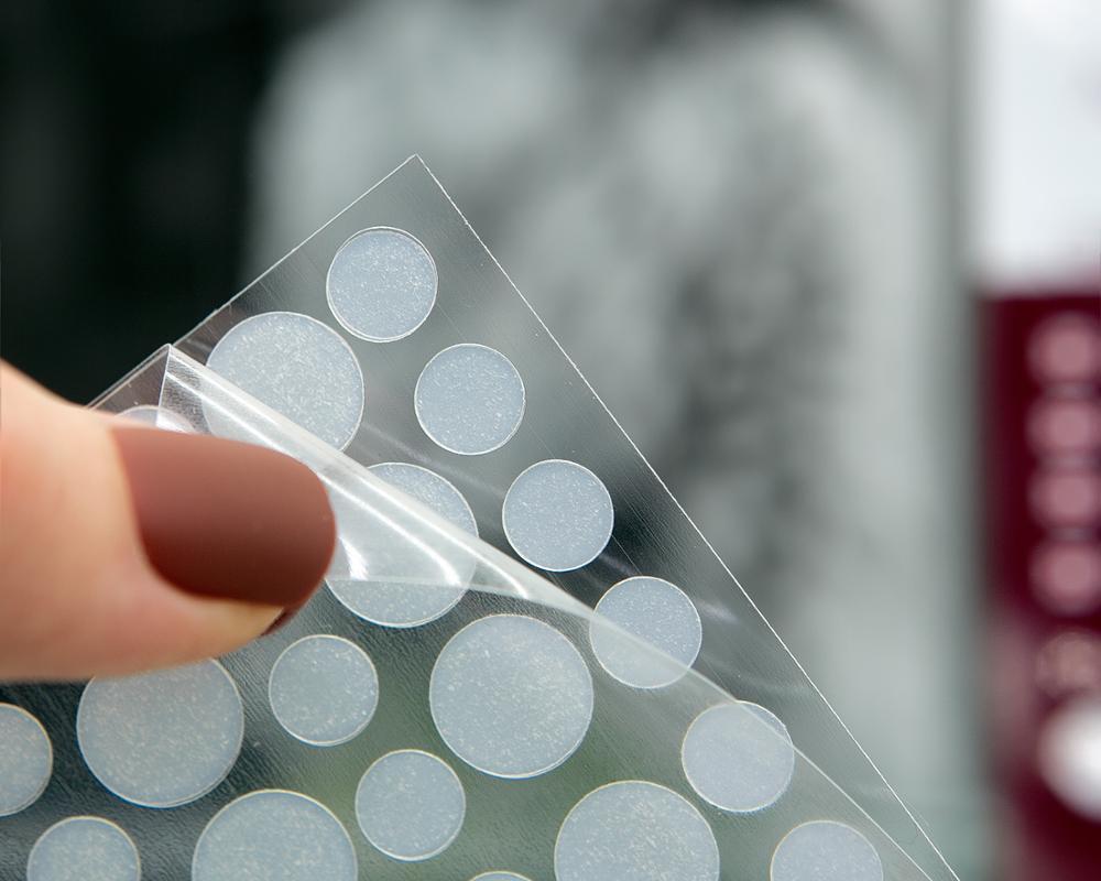 Sheet of round adhesive stickers held by a hand with a blurred background